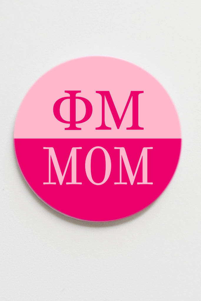 Pink and white circular sticker with 'ΦM MOM' text on a light gray background