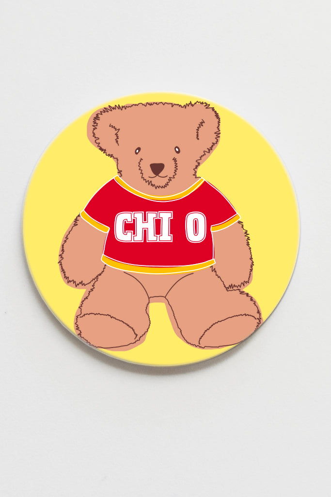Round coaster with a teddy bear wearing a red shirt on a yellow background