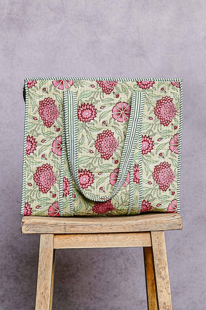 Floral-patterned bag on a wooden stool against a gray background