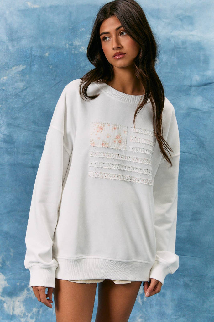 Woman wearing a white sweatshirt with lace details against a blue textured background