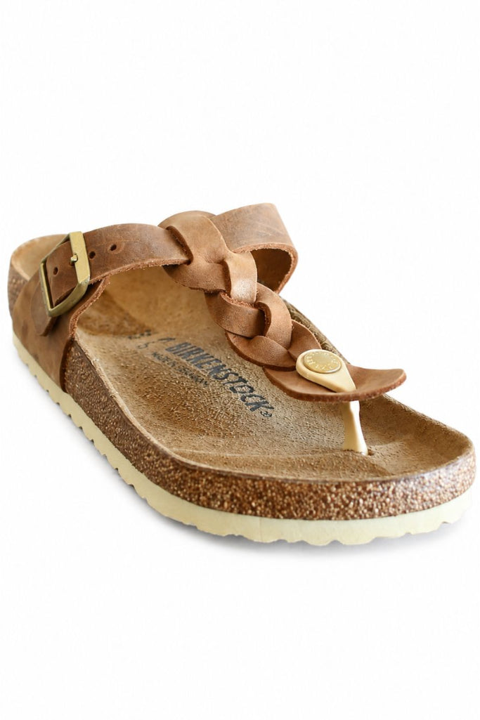 A single brown leather thong sandal with a braided strap detail, a buckle on the back, and a cork-textured footbed, shown on a plain white background.