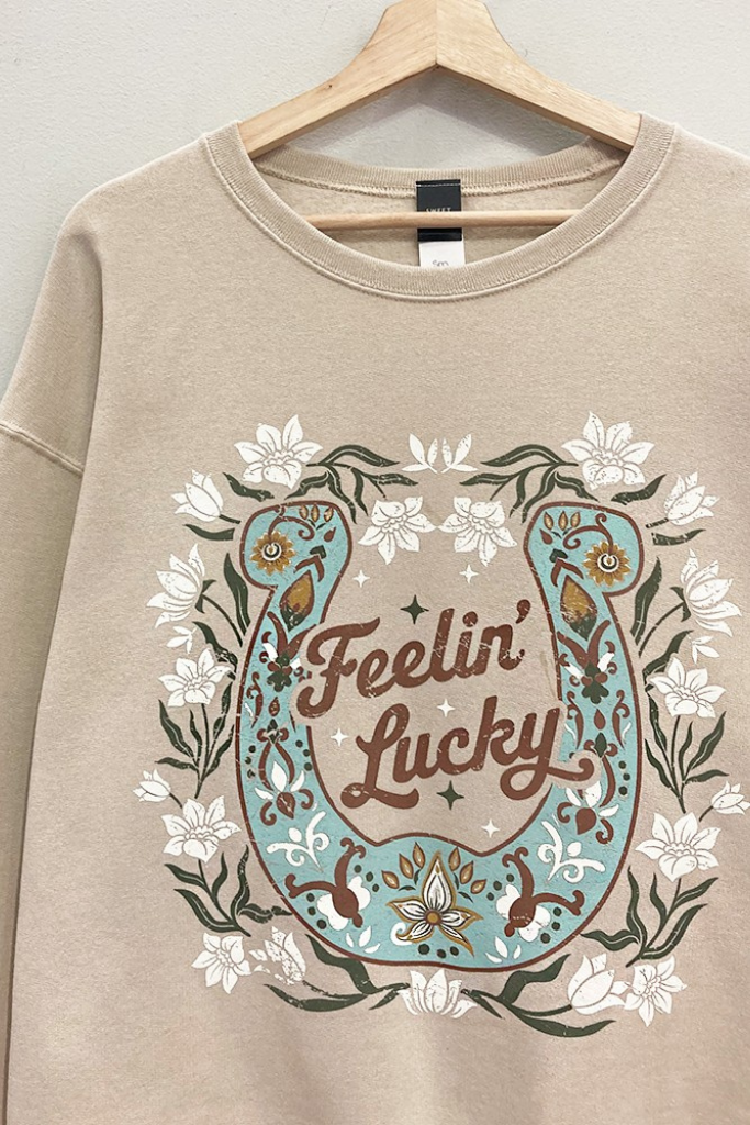 Close-up of floral horseshoe Feelin' Lucky graphic on taupe sweatshirt