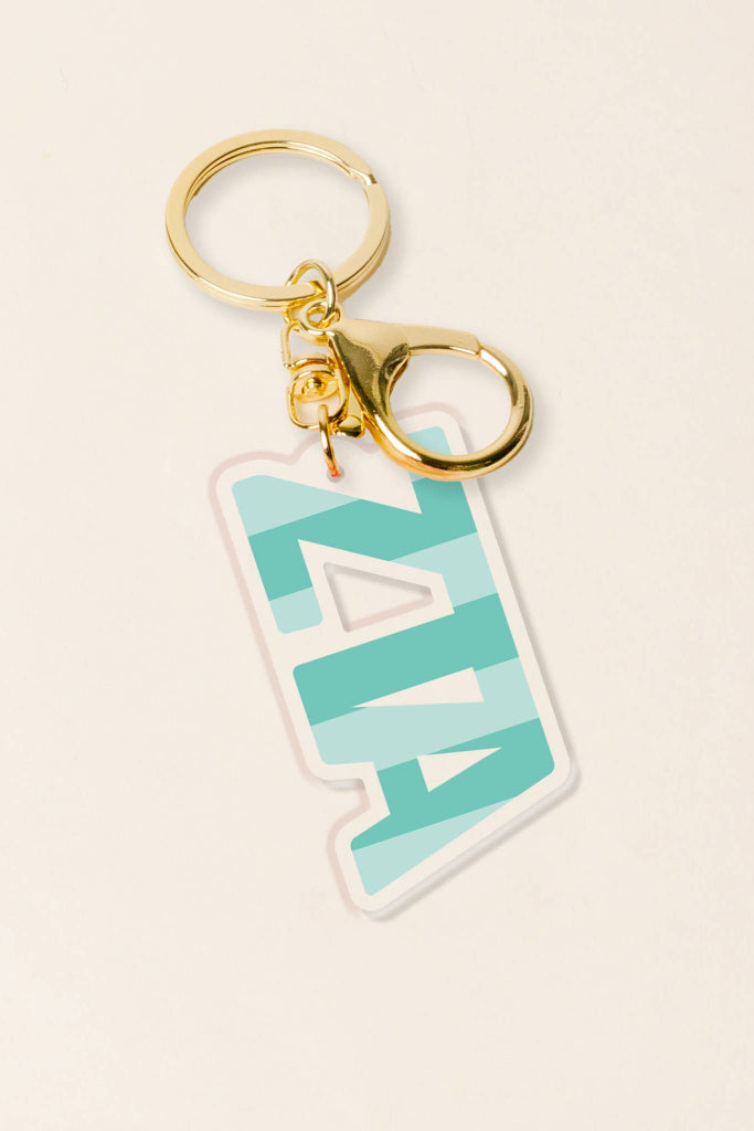 Keychain with a turquoise and white design on a beige background