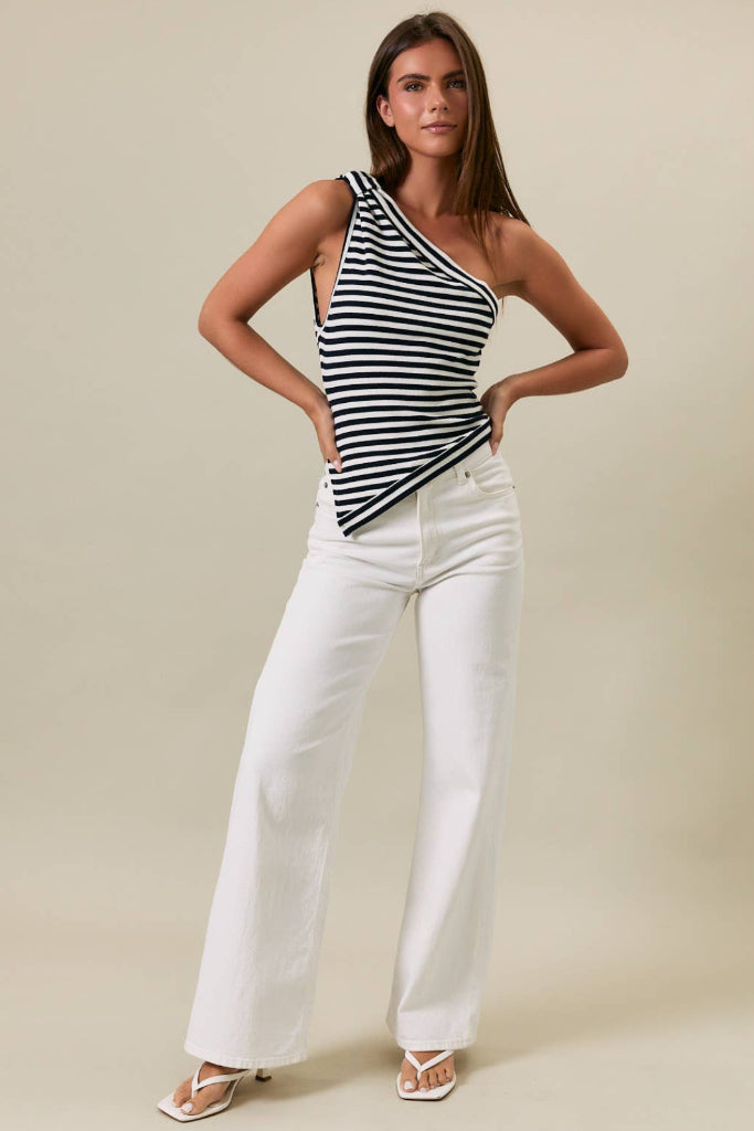 Woman wearing a navy and white striped top and white pants against a beige background