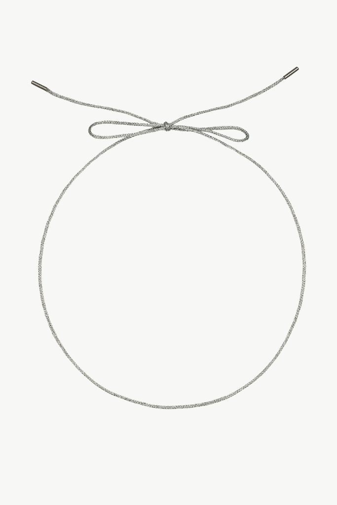 A silver-toned rope necklace with a knotted top and a small metal clasp at the end, displayed on a clean off-white background.