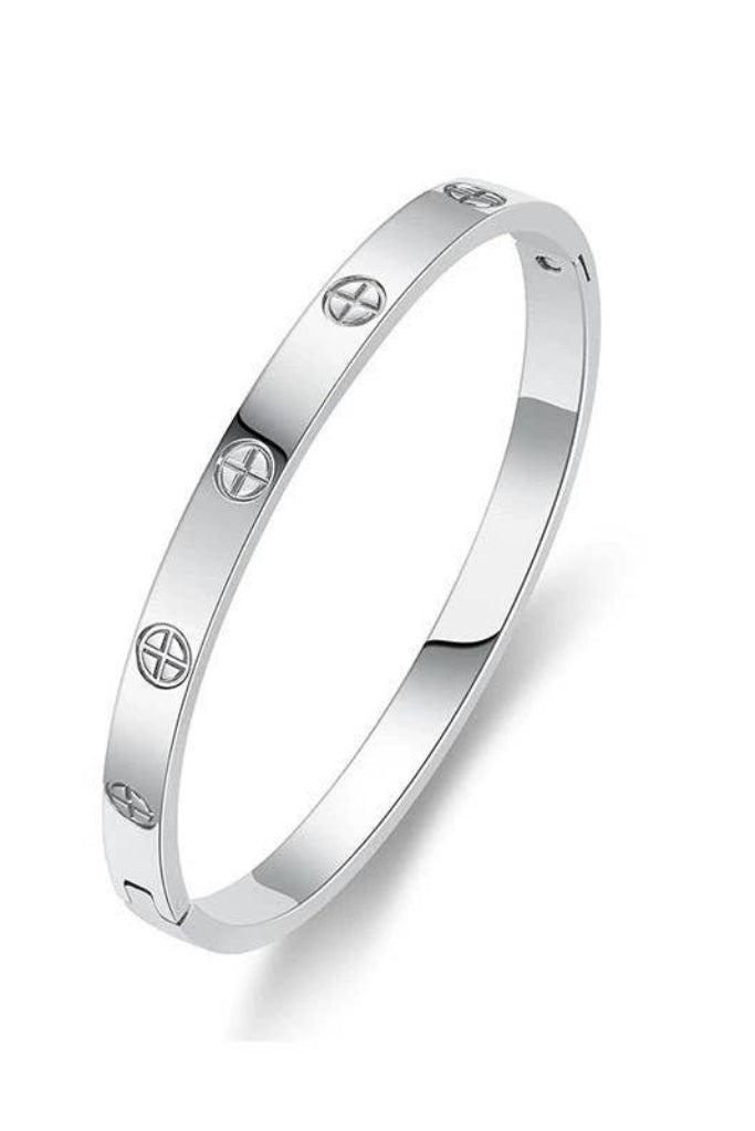 A polished silver-toned bangle bracelet with evenly spaced screw-head motifs, shown on a clean white background.