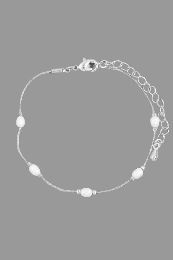 Silver bracelet with white beads on a gray background