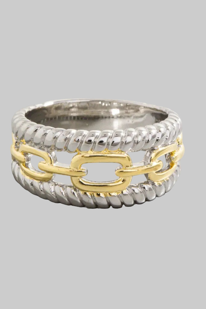 Two rings, one gold and one silver, stacked on a light gray background