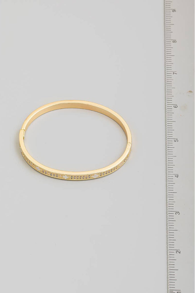 Gold ring with embedded stones next to a ruler on a gray background