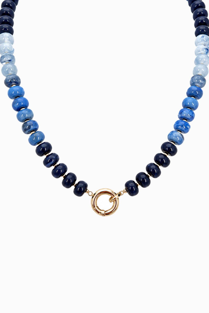 A beaded necklace featuring alternating strands of polished dark navy, medium blue, and light blue beads, finished with a central gold-tone split ring clasp, shown against a plain white background.