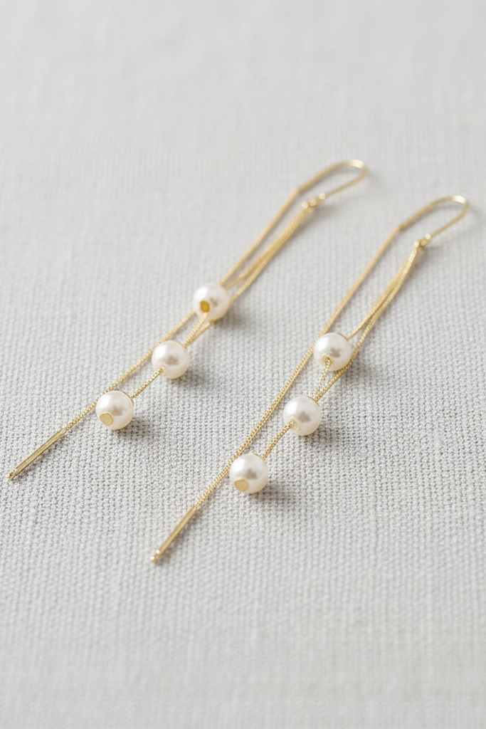 Pair of pearl earrings on a light gray fabric background