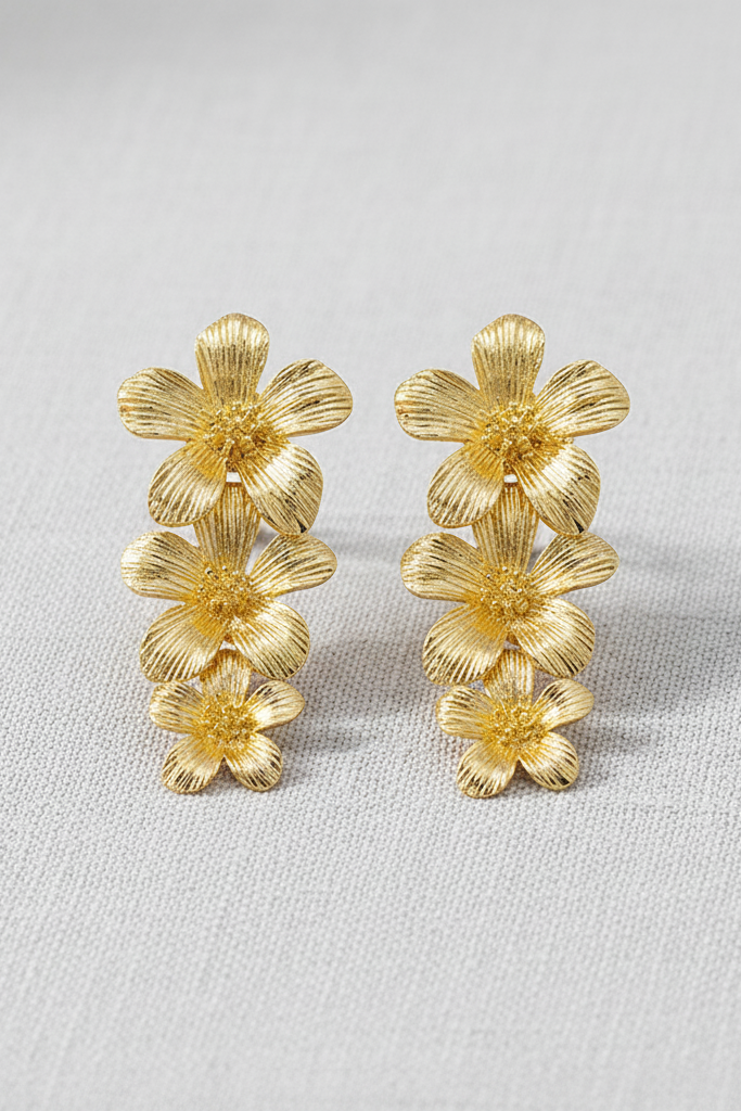 Pair of gold floral earrings on a light gray background