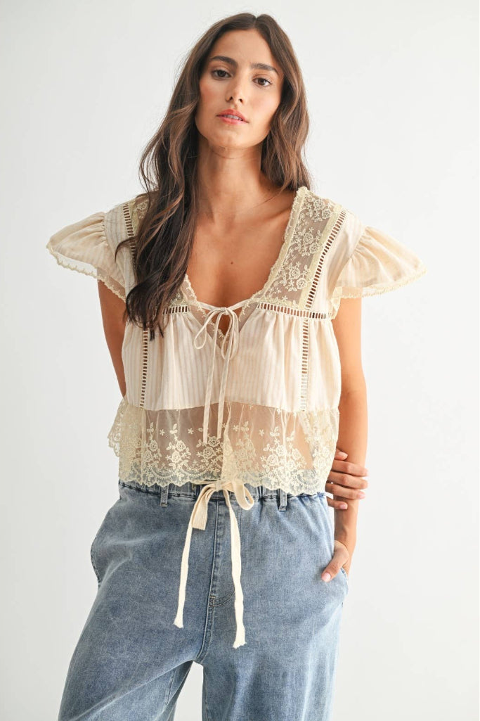 Woman wearing a lace top and jeans on a white background