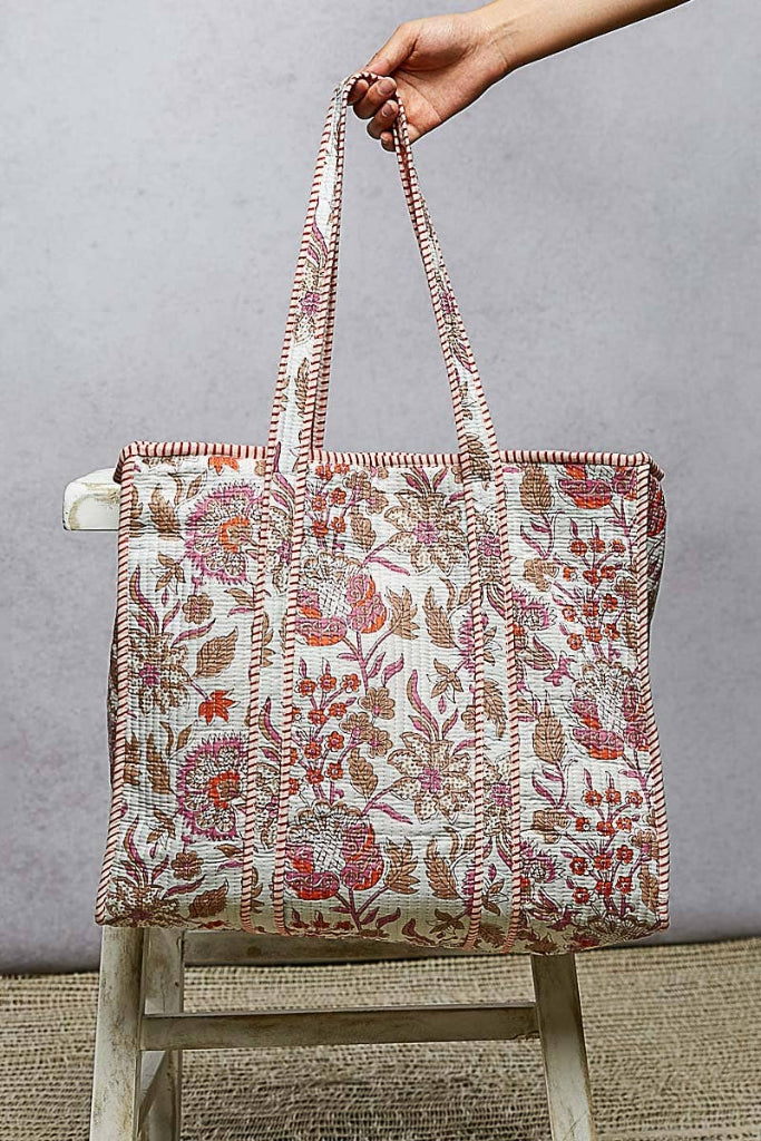 Floral patterned tote bag held by a hand against a gray background