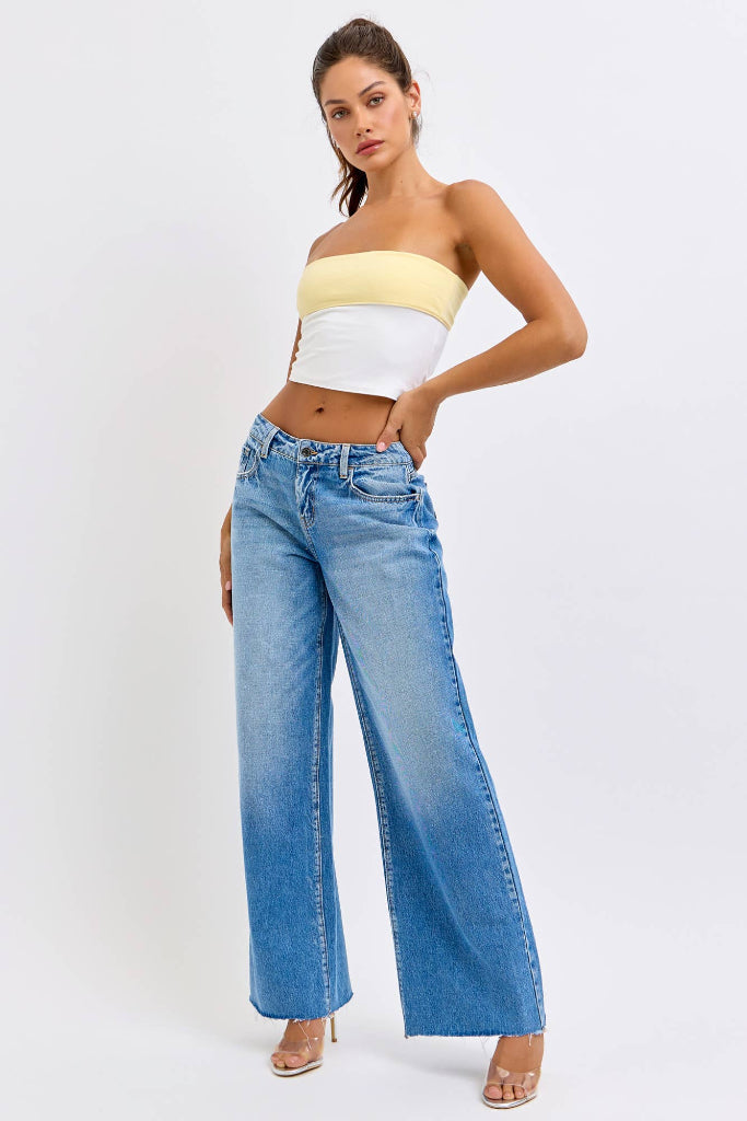 Woman wearing a strapless top and wide-leg jeans on a white background