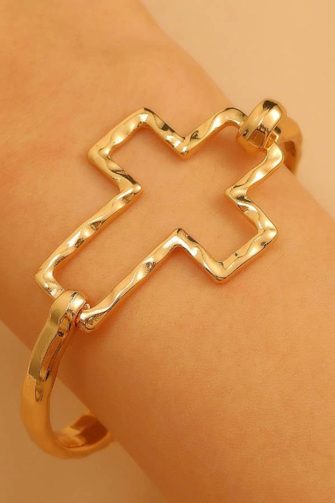 Gold star-shaped bracelet on a wrist against a beige background