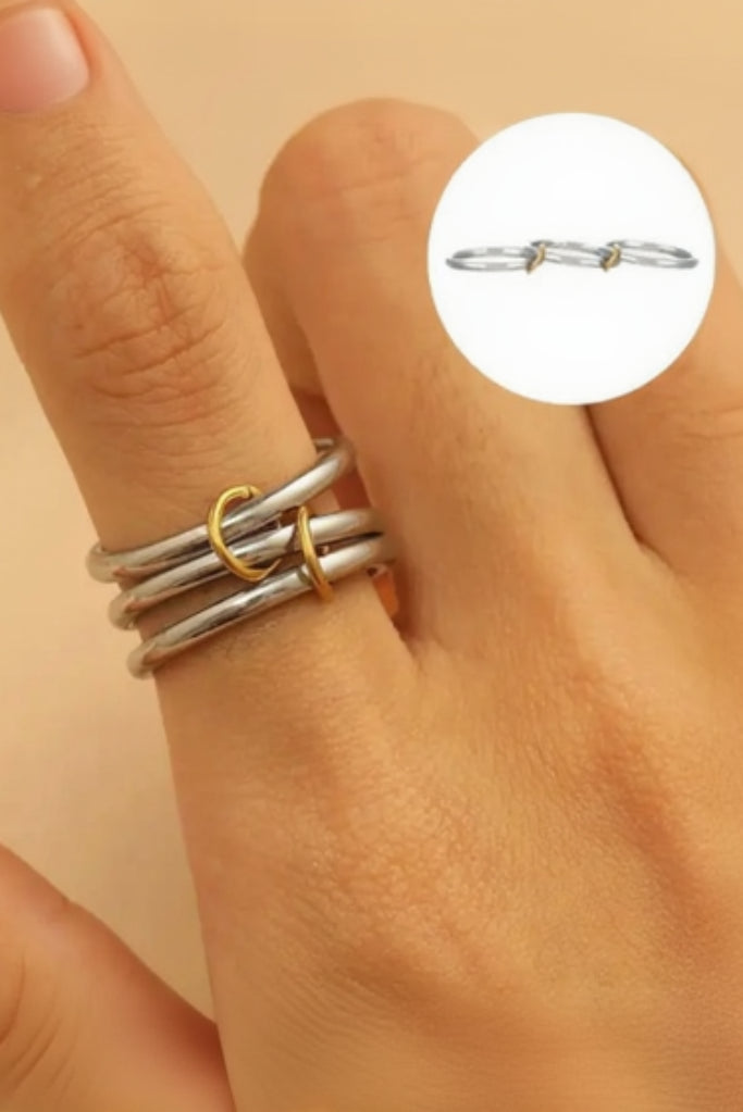 Stack of silver and gold rings on a hand with a beige background