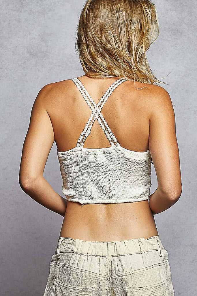 Person wearing a white crop top with criss-cross back design on a gray background
