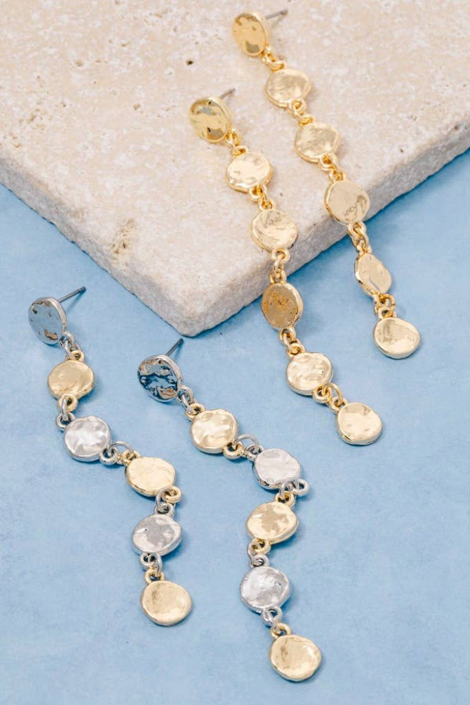 Gold and silver beaded earrings on a stone and blue surface