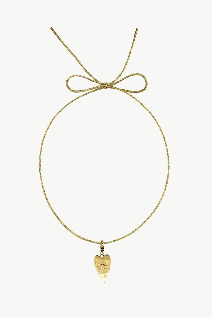 A delicate gold cord necklace with a small gold heart pendant, featuring an adjustable tie at the top, displayed against a solid off-white background.