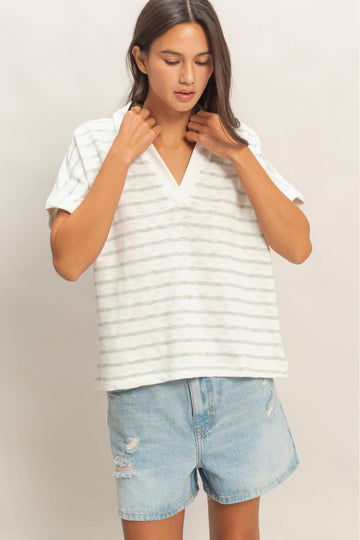 Woman wearing a white striped shirt and denim shorts on a plain background