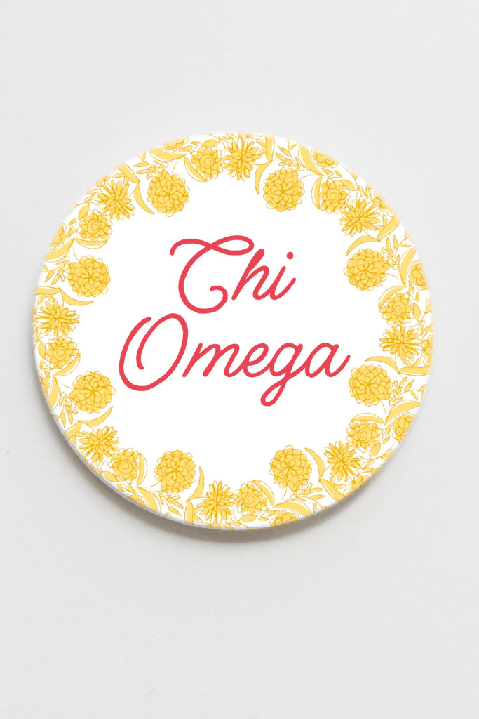 Circular coaster with 'Chi Omega' text and yellow floral pattern on a white background