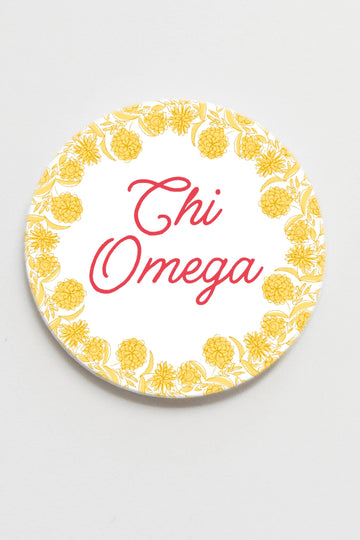Circular coaster with 'Chi Omega' text and yellow floral pattern on a white background