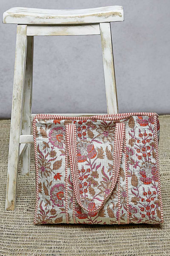 Floral patterned blanket draped over a wooden stool against a gray background