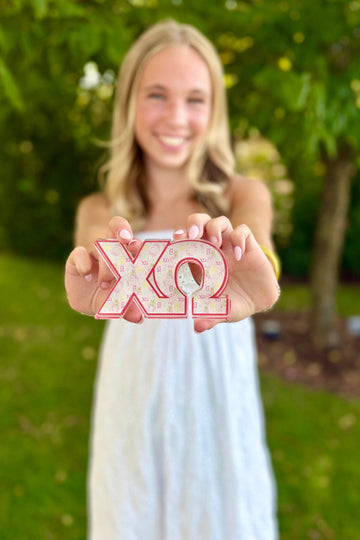 Woman holding up a pink 'ΧΩ' sign outdoors