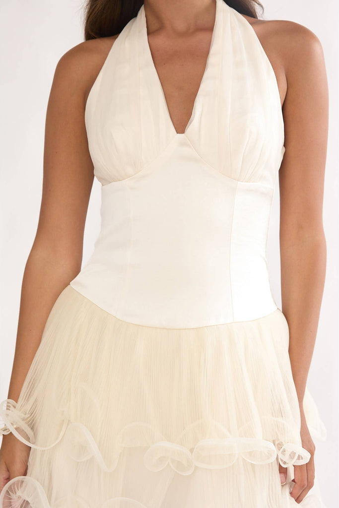 Woman wearing a white halter top and beige skirt on a white background