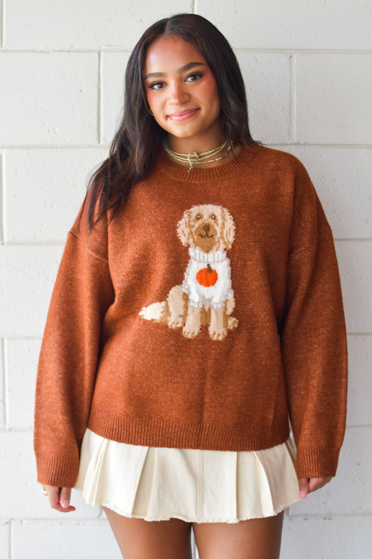 Woman wearing cognac crew neck sweater with doodle dog in a pumpkin sweater design