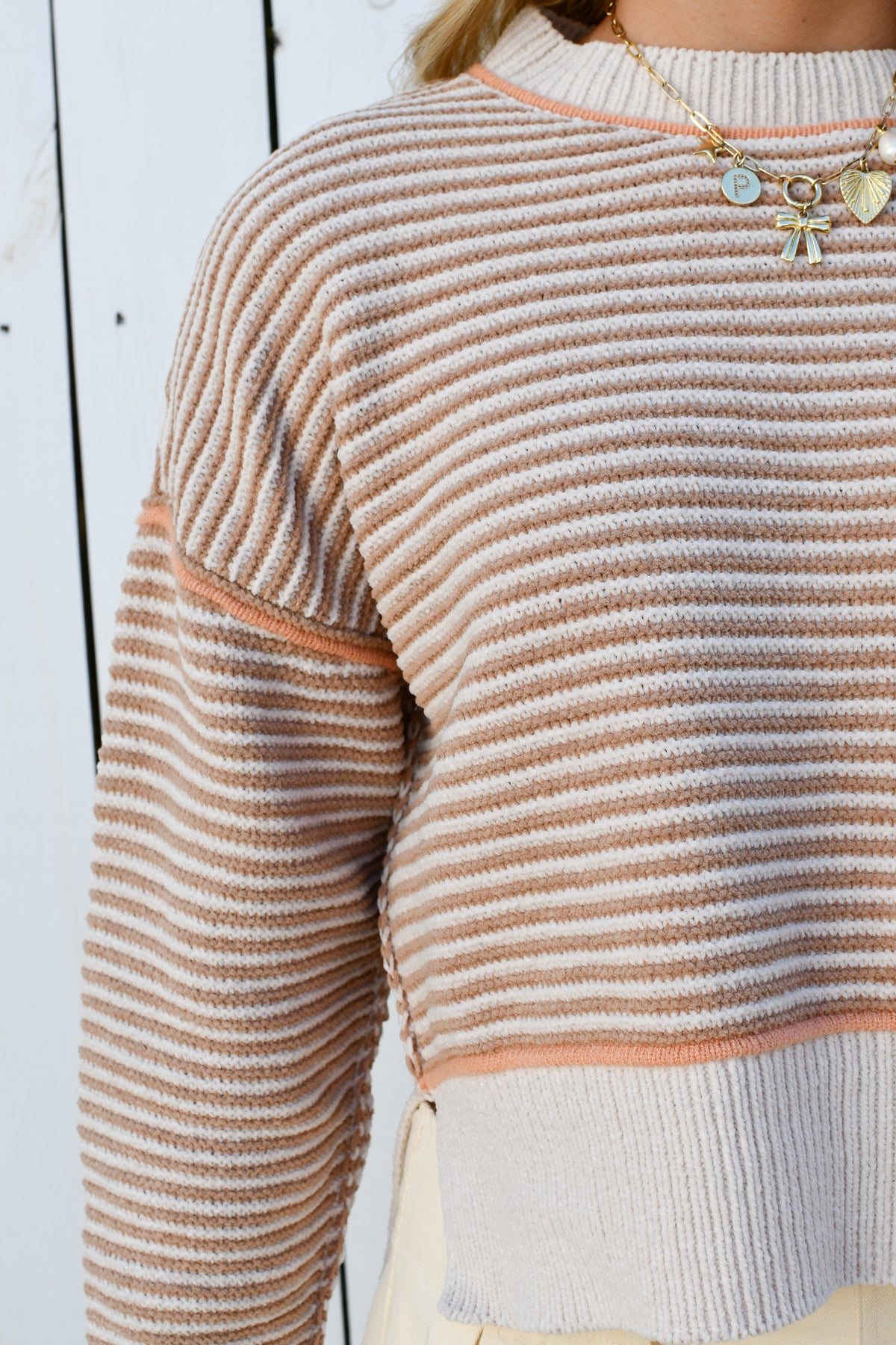 Close-up of beige and rust stripes and contrast trim on knit sweater