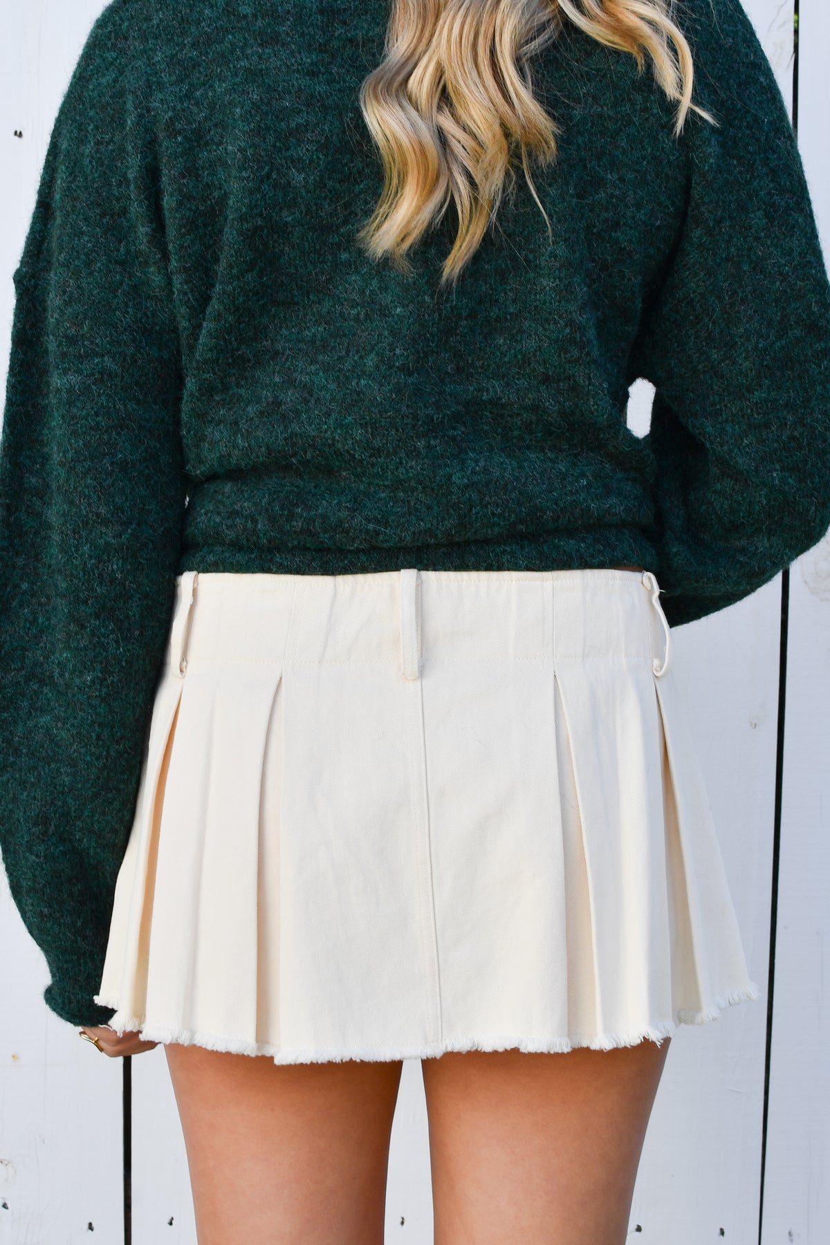 Back of cream pleated mini skort with frayed hem