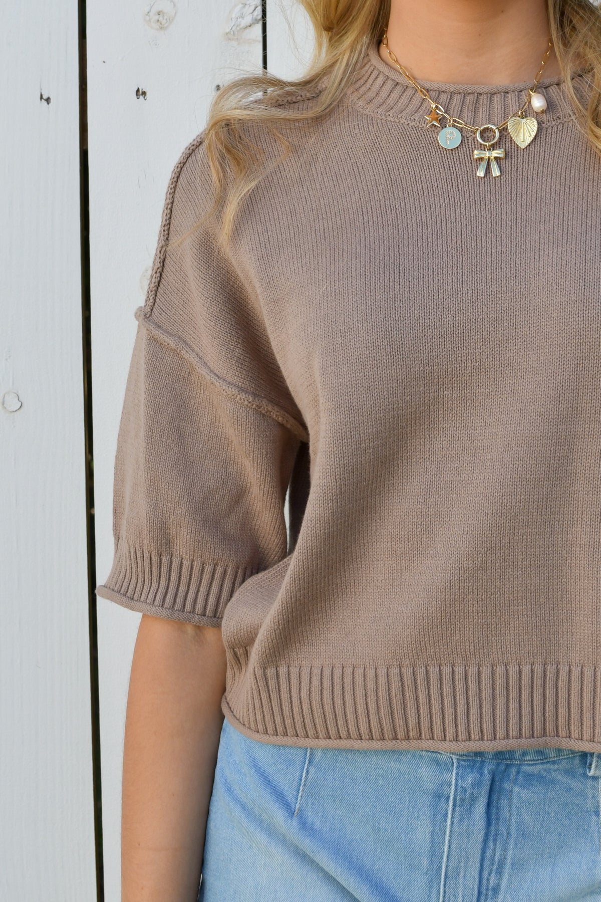 Close-up of taupe knit top neckline and drop-shoulder sleeve