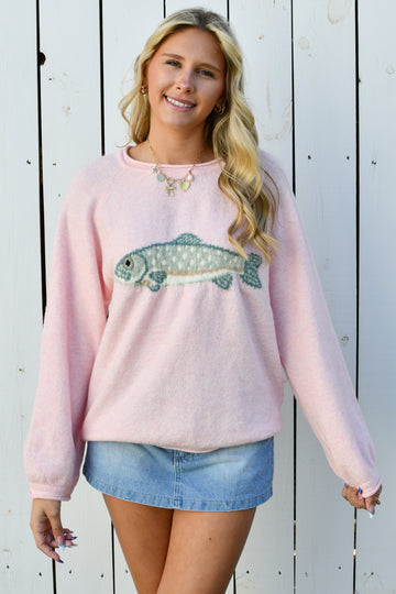 Model wearing pink fuzzy crewneck sweater with fish design
