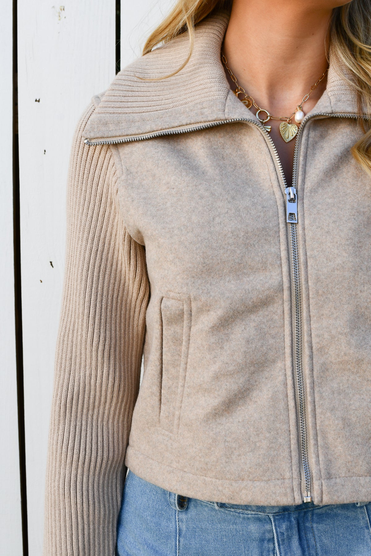 Close-up of taupe knit jacket collar, zipper and ribbed sleeve