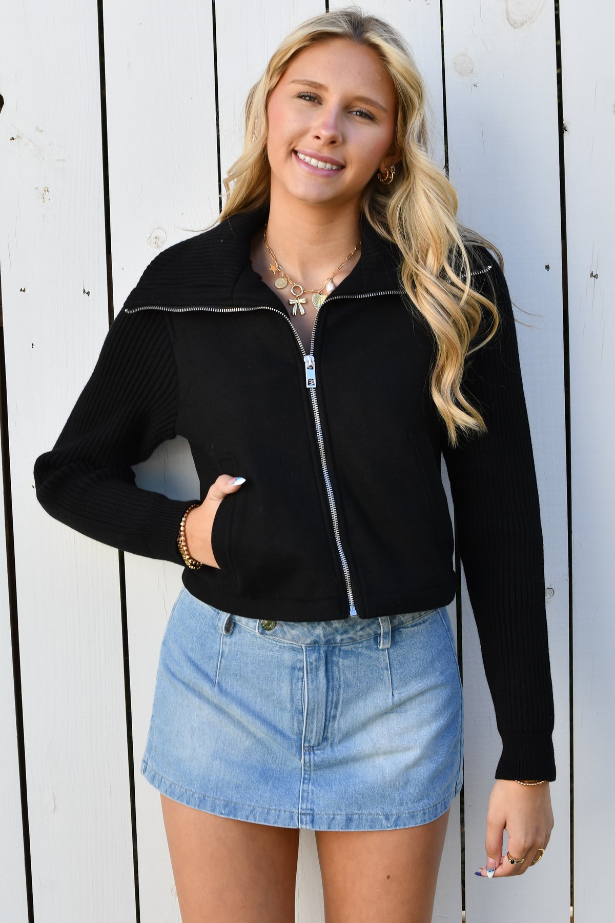 Black zip knit jacket shown with hand in pocket