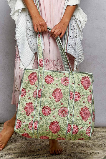 Person holding a floral-patterned tote bag against a gray background