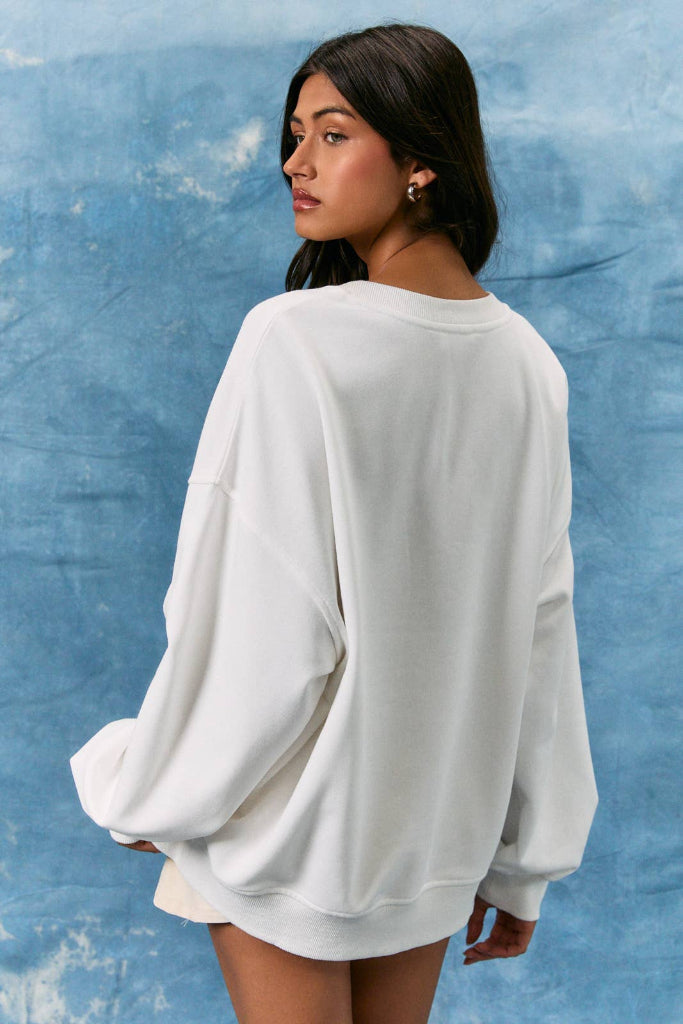 Woman wearing a white sweatshirt with lace details against a blue textured background