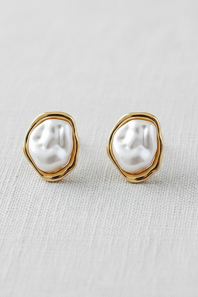 Pair of pearl earrings with gold frames on a light gray background