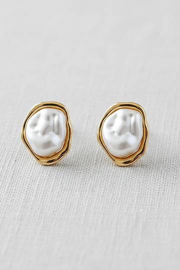 Pair of pearl earrings with gold frames on a light gray background