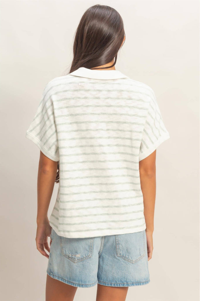 Woman wearing a white striped shirt and denim shorts on a plain background