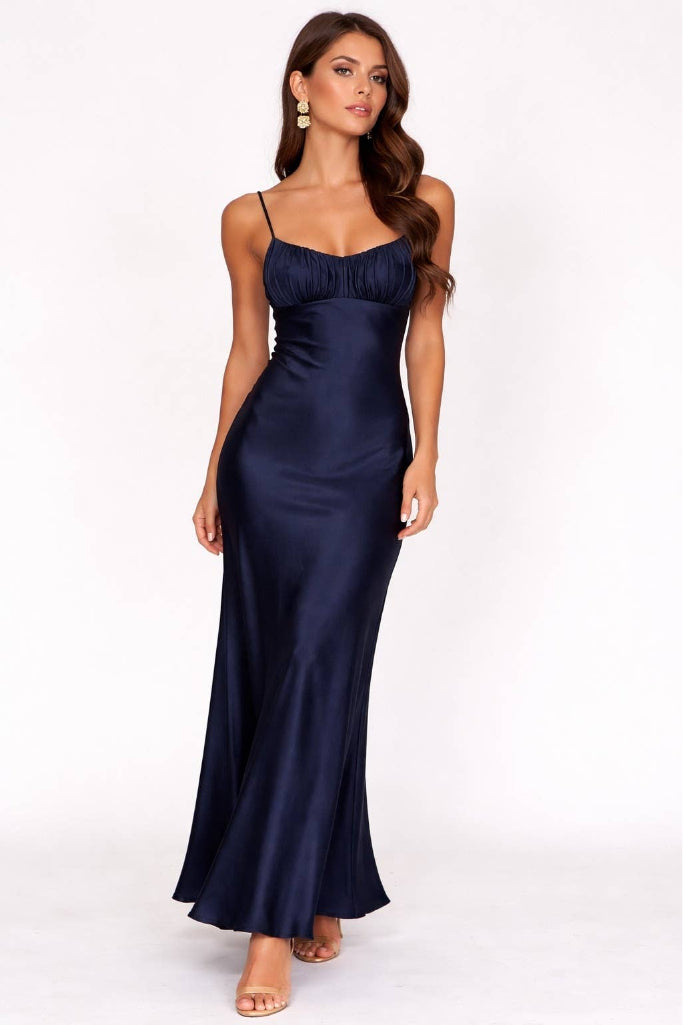 Woman wearing a navy blue satin gown on a white background