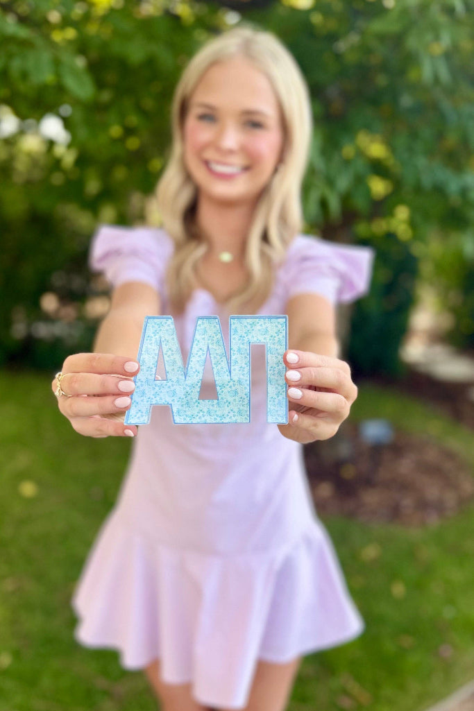 Woman holding up letters 'AAT' outdoors