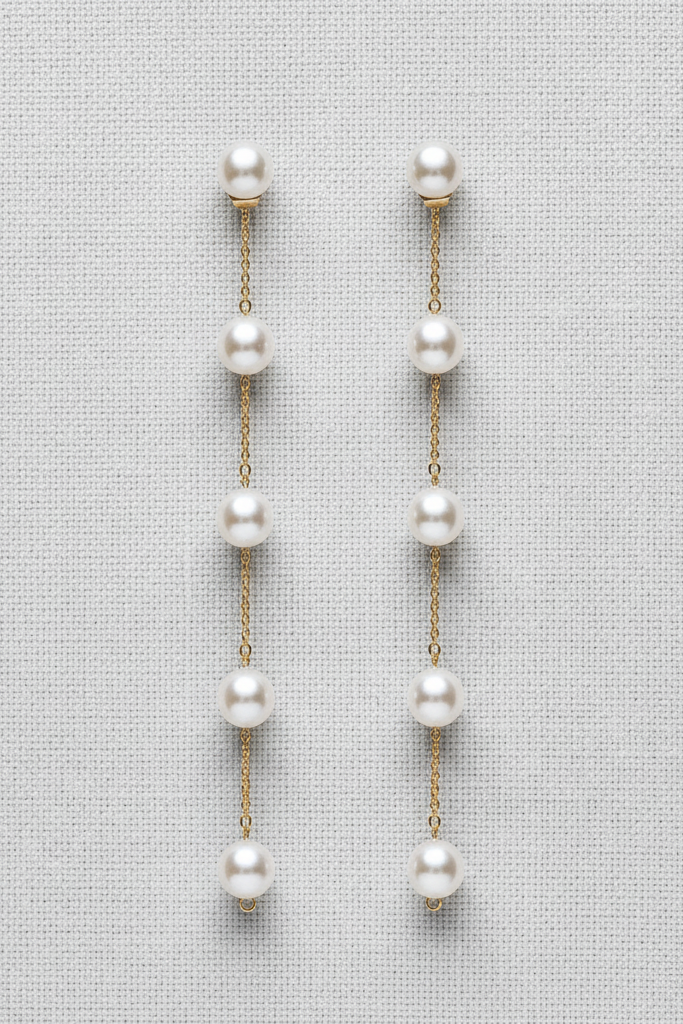 Pair of pearl earrings on a light gray fabric background