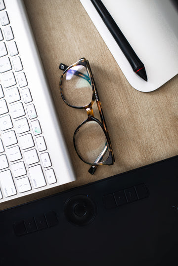 CLOSE-UP-OF-EYE-GLASSES-ON-A-COMPUTER-DESK