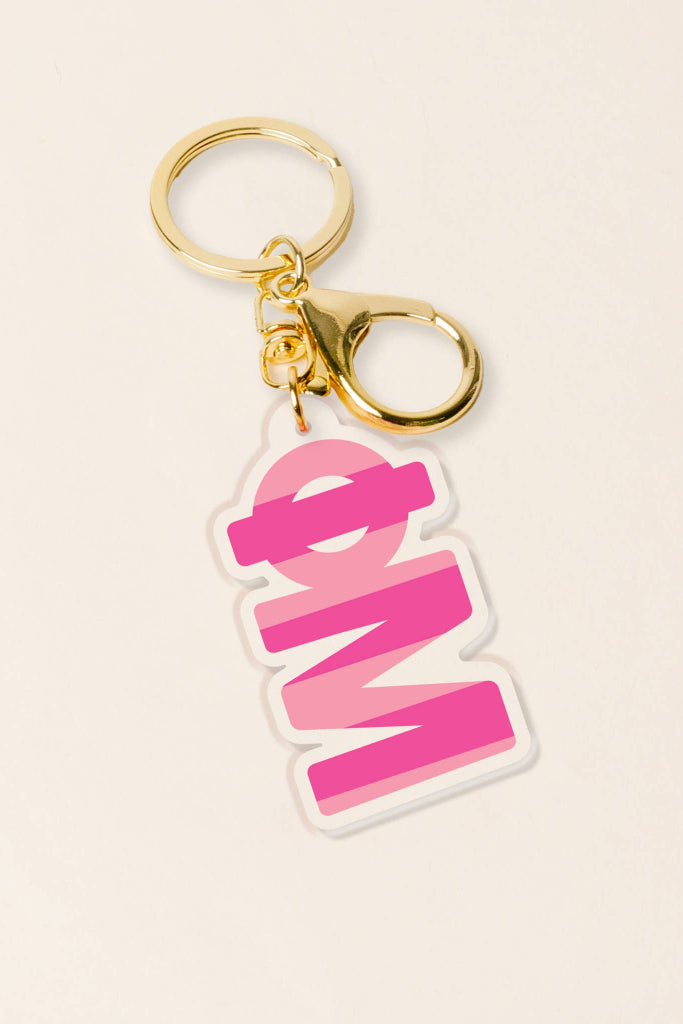 Keychain with pink 'OM' design on a beige background