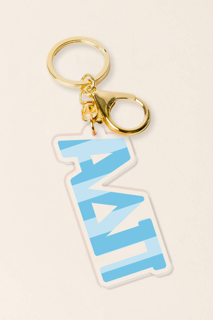 Keychain with blue zigzag design and gold clasp on beige background