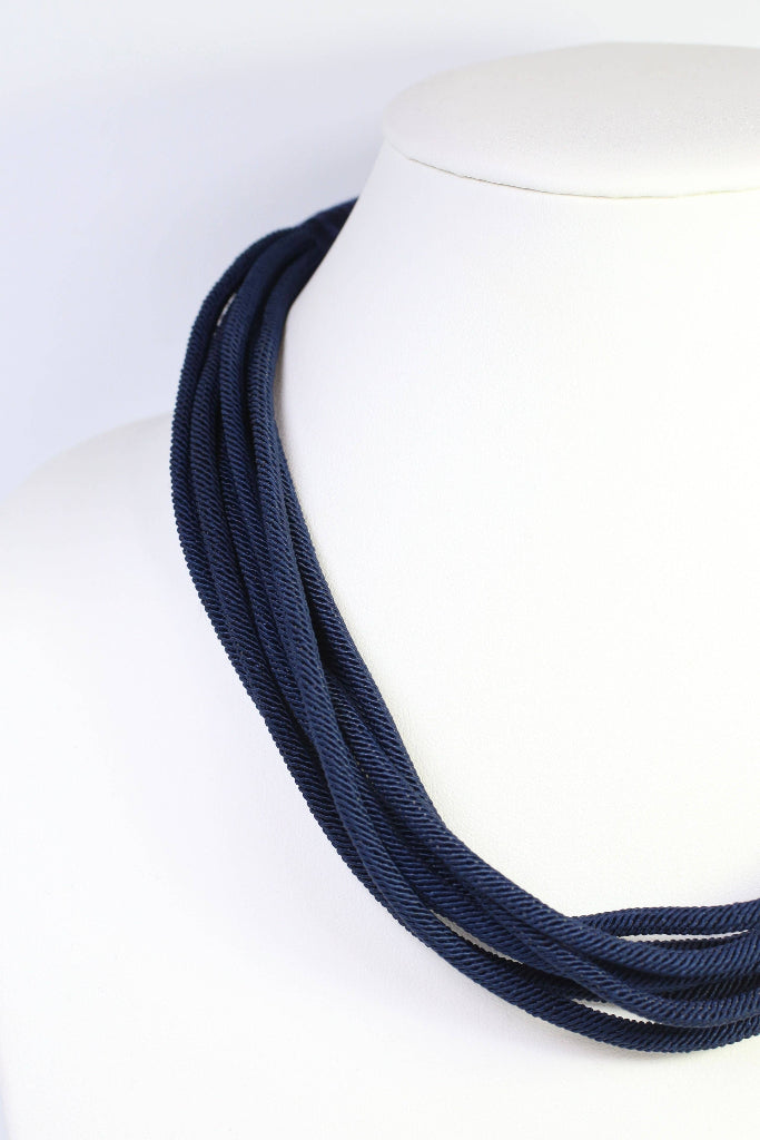 Navy blue necklace on a mannequin with a white background