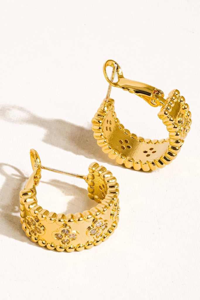 Gold hoop earrings with intricate designs on a white background